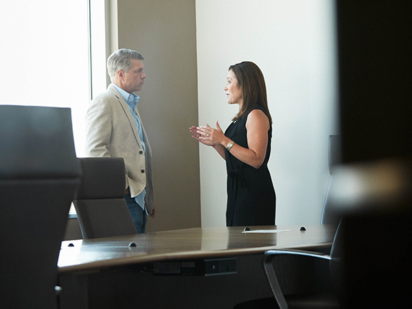A professional man and woman having a discussion in a conference room