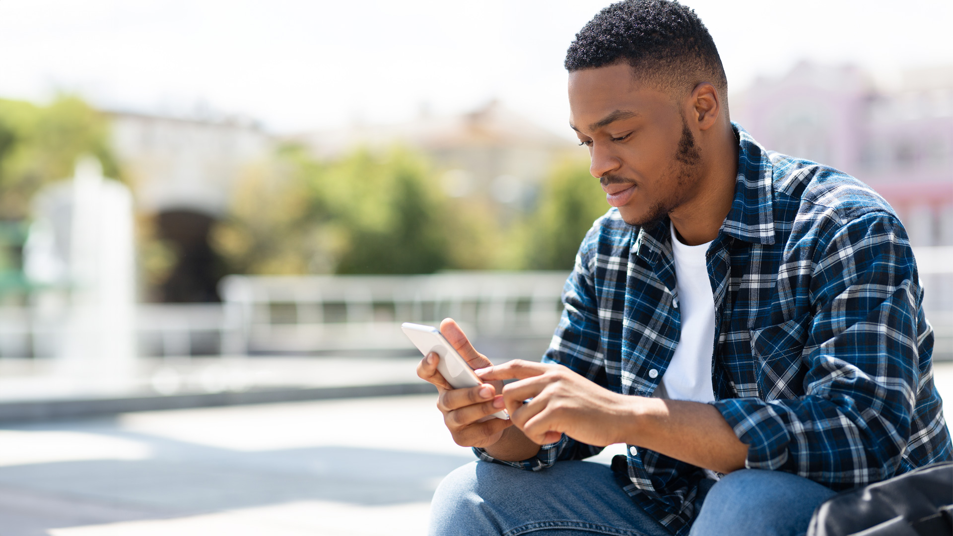 Young African male uses smart phone for SMS
